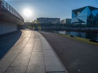 a skateboarder riding on a cement ramp next to a city street under a bridge