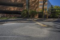 this is a road with a yellow street sign and trees in front of it, with buildings and blue sky