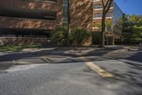 this is a road with a yellow street sign and trees in front of it, with buildings and blue sky