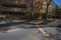 this is a road with a yellow street sign and trees in front of it, with buildings and blue sky