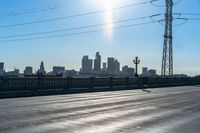 the sun is shining down over a highway with city buildings in the distance and blue skies