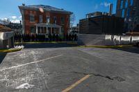 a small parking lot with no cars in front of a building and a fenced off street area