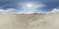 this panorama looks like desert area with snowboarders in it and some hills on the far side of the photograph