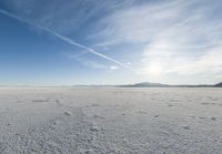 snow covered plain in bright sunlight and clear blue sky behind it at the bottom of the hill