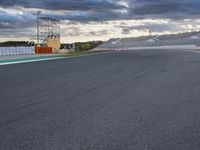 an empty track with a few cones and sky background at a race track while the sun sets