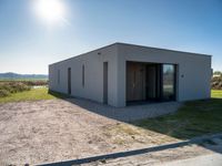 a concrete building that has an open door and a flat roof, sitting in the middle of a field