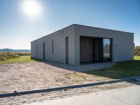 a concrete building that has an open door and a flat roof, sitting in the middle of a field