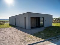 a concrete building that has an open door and a flat roof, sitting in the middle of a field