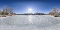 a panoramic view of snow and a dock with trees surrounding it with an image of an empty park bench