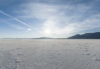 footprints on the snow of a vast open plain with a bright sky in the background