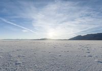 footprints on the snow of a vast open plain with a bright sky in the background