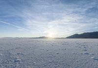 footprints on the snow of a vast open plain with a bright sky in the background