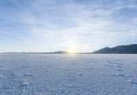 footprints on the snow of a vast open plain with a bright sky in the background