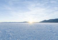 footprints on the snow of a vast open plain with a bright sky in the background