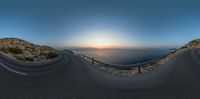 an amazing view of the sun rising over mountains and sea and a curved road is shown through the lens