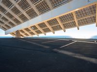 the underside of a building with solar panels on it's sides, overlooking the water and beach