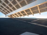 the underside of a building with solar panels on it's sides, overlooking the water and beach