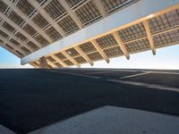 the underside of a building with solar panels on it's sides, overlooking the water and beach