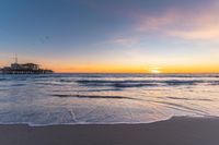 a beach scene during sunrise with the water still up to the ground and the ocean in the background