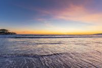 a beach scene during sunrise with the water still up to the ground and the ocean in the background