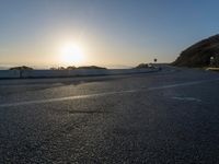 the sun is rising over the ocean on a road with a couple of bikers