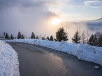 the sun is rising over a long, empty road and mountain range covered in snow