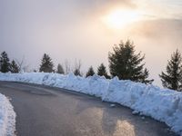 the sun is rising over a long, empty road and mountain range covered in snow