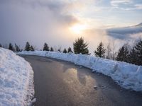 the sun is rising over a long, empty road and mountain range covered in snow