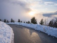the sun is rising over a long, empty road and mountain range covered in snow