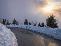 the sun is rising over a long, empty road and mountain range covered in snow