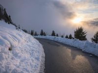 the sun is rising over a long, empty road and mountain range covered in snow