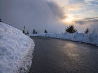 the sun is rising over a long, empty road and mountain range covered in snow