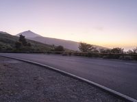 a highway with a mountain view at sunrise over mountains near the road with cars passing