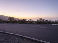 a highway with a mountain view at sunrise over mountains near the road with cars passing