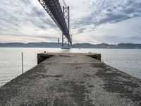 a very old concrete pier extending out into the water and clouds over the bay and the golden gate bridge