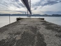 a very old concrete pier extending out into the water and clouds over the bay and the golden gate bridge