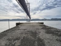 a very old concrete pier extending out into the water and clouds over the bay and the golden gate bridge