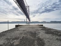 a very old concrete pier extending out into the water and clouds over the bay and the golden gate bridge