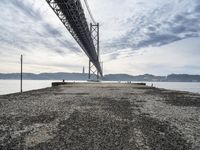 a very old concrete pier extending out into the water and clouds over the bay and the golden gate bridge