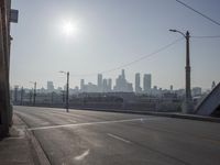 view of city from an open empty road at the intersection of a highway, with cars parked along it
