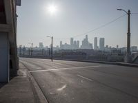 view of city from an open empty road at the intersection of a highway, with cars parked along it