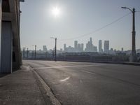 view of city from an open empty road at the intersection of a highway, with cars parked along it