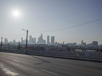 view of city from an open empty road at the intersection of a highway, with cars parked along it