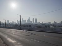 view of city from an open empty road at the intersection of a highway, with cars parked along it