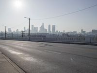 view of city from an open empty road at the intersection of a highway, with cars parked along it