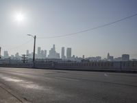 view of city from an open empty road at the intersection of a highway, with cars parked along it