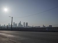 view of city from an open empty road at the intersection of a highway, with cars parked along it
