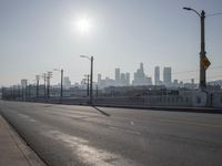 view of city from an open empty road at the intersection of a highway, with cars parked along it