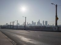 view of city from an open empty road at the intersection of a highway, with cars parked along it