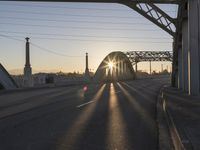 a train moving on a bridge at sunrise over the street and cars driving on the road